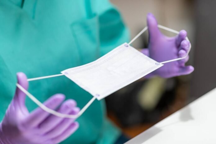 Hands in protective gloves holding protective mask